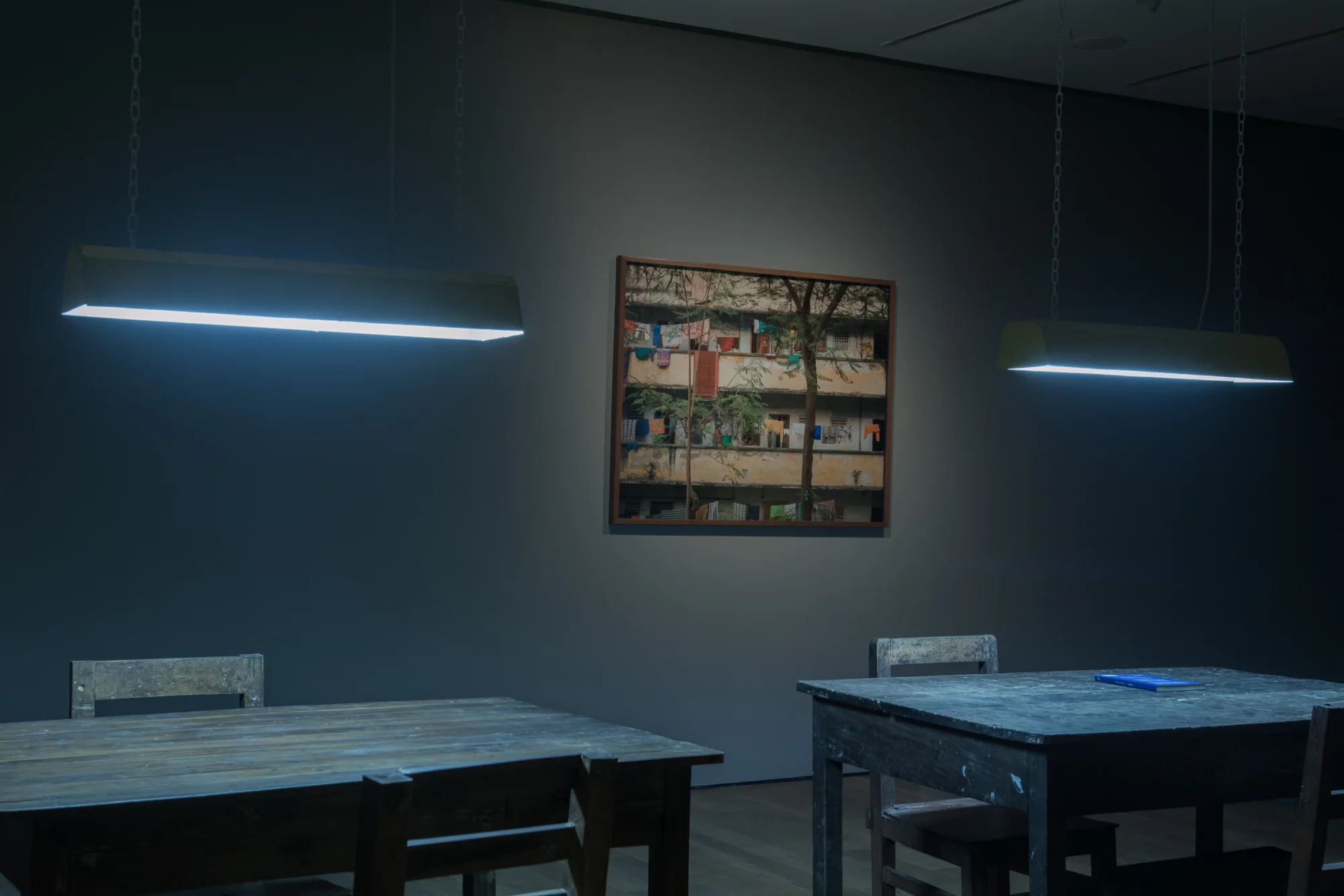 Tables and chairs beneath hanging fluorescent lights in the Age of Saturn exhibition