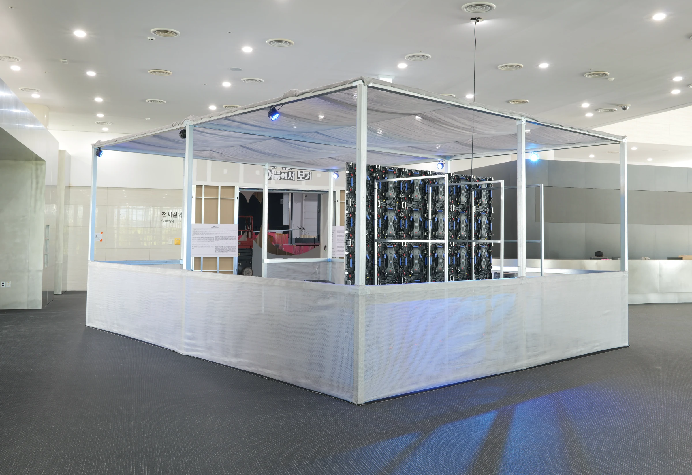 Rear installation view of the aluminium-and-mesh BAN♡ITS pavilion and exposed LED wall at Busan Biennale