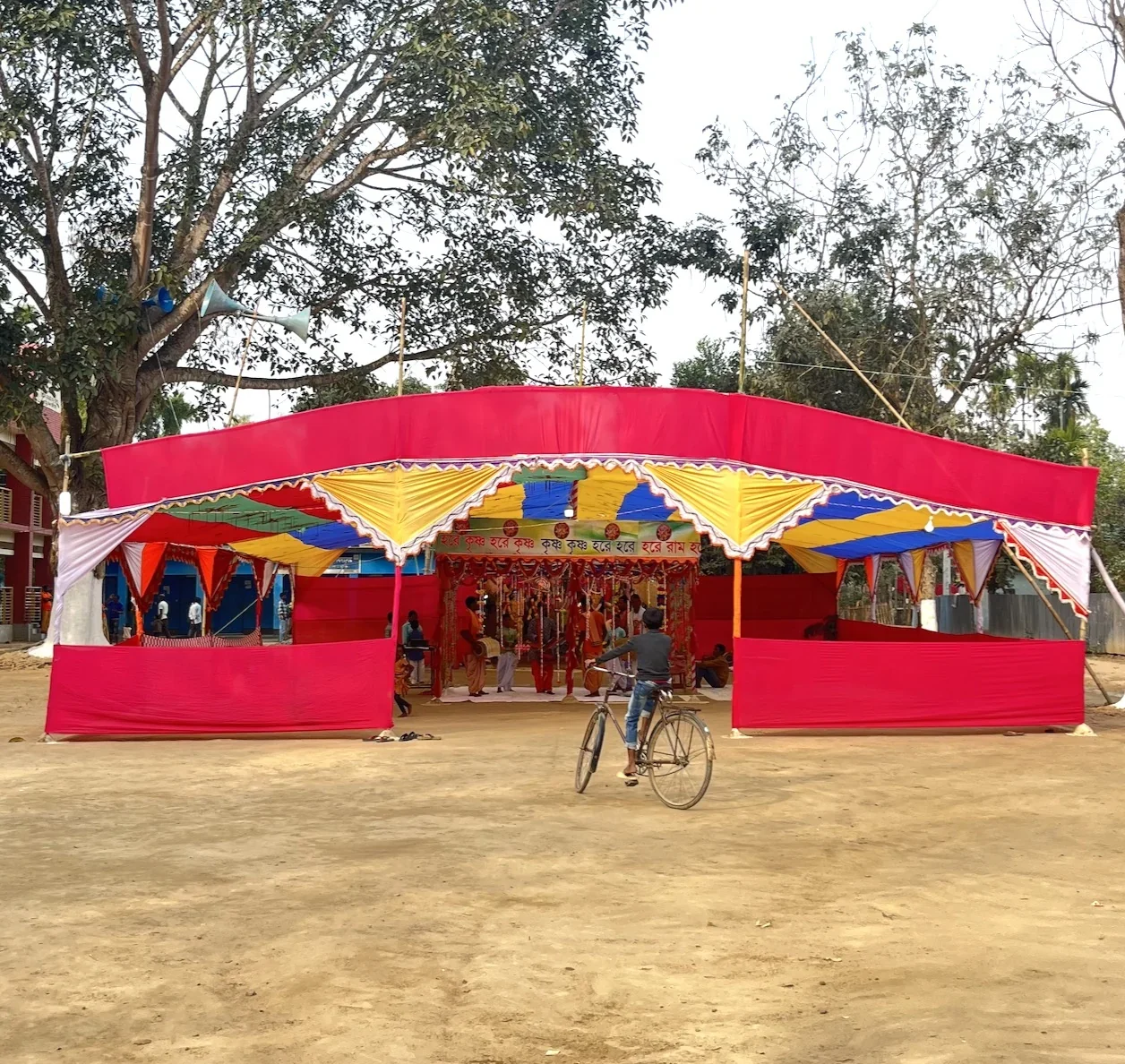 A brightly coloured temporary pavilion with a cyclist approaching its entrance