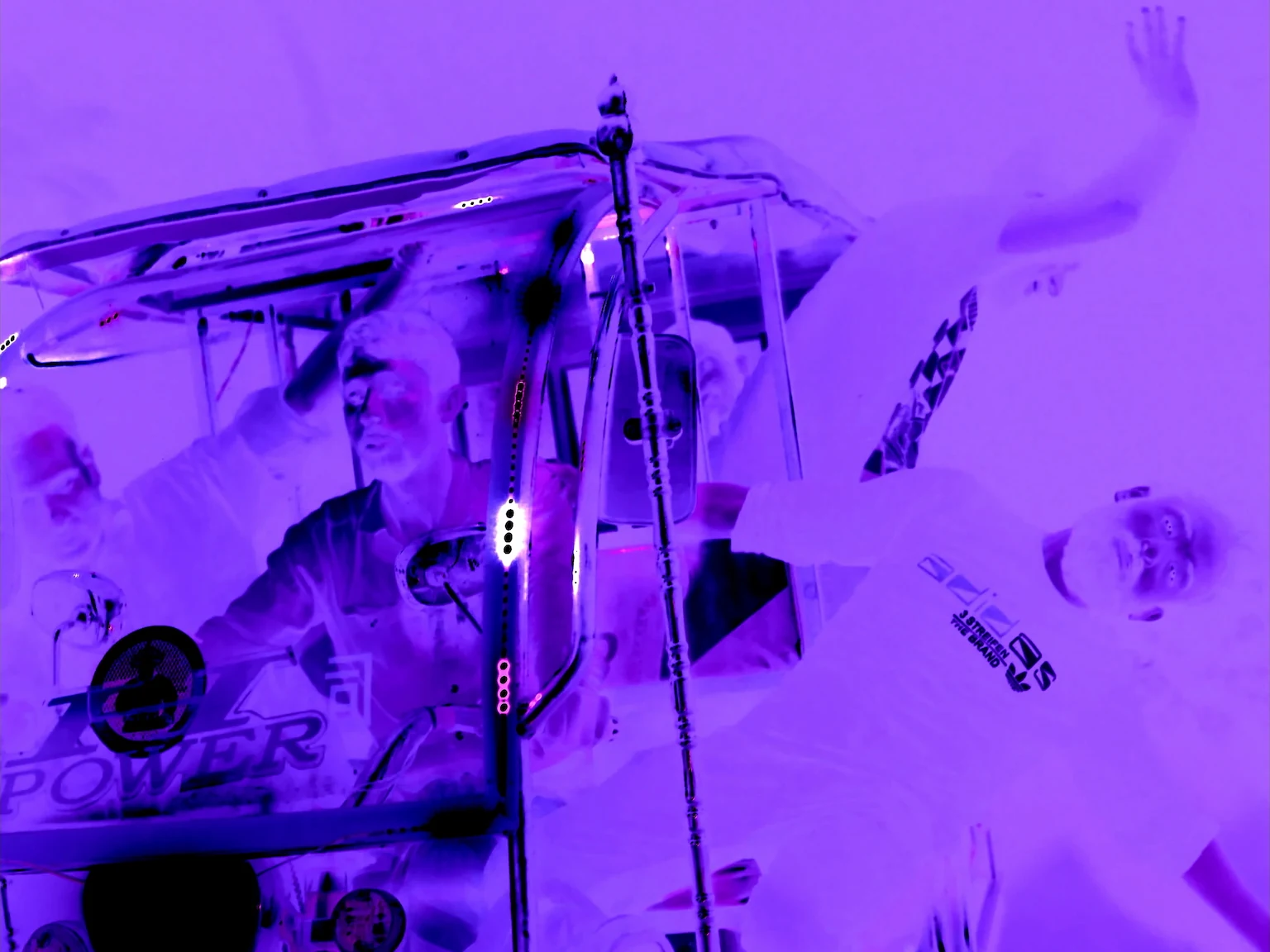 Bandits gathered around a decorated three-wheeler in a purple inverted film still