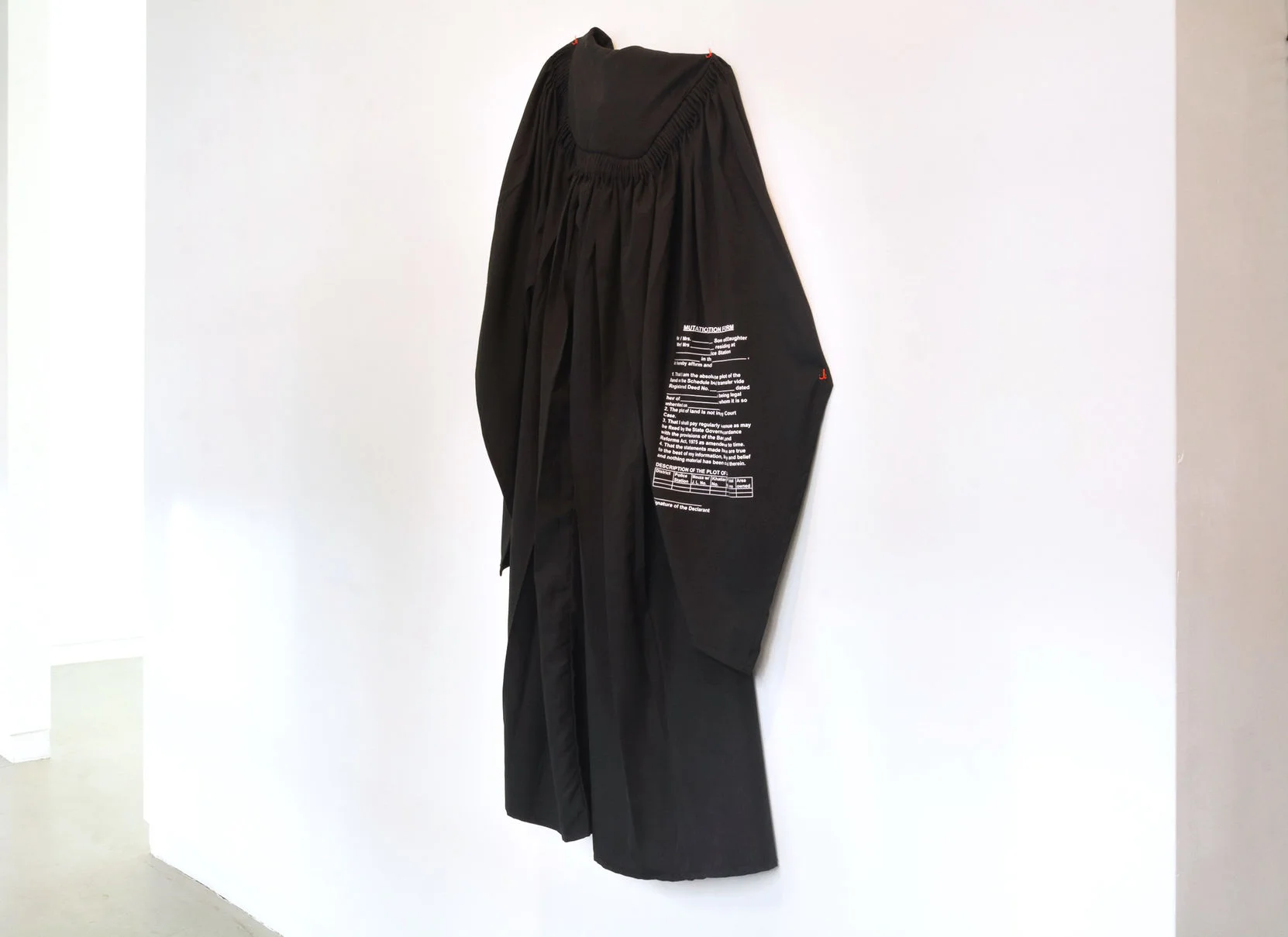 Black barrister’s gown suspended on orange hooks