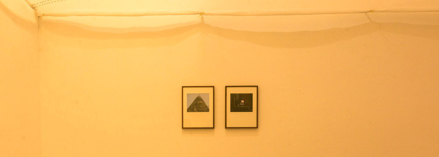 Netting above two framed photographs in an installation view