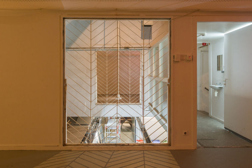 Installation view through a window grille towards the shared facilities