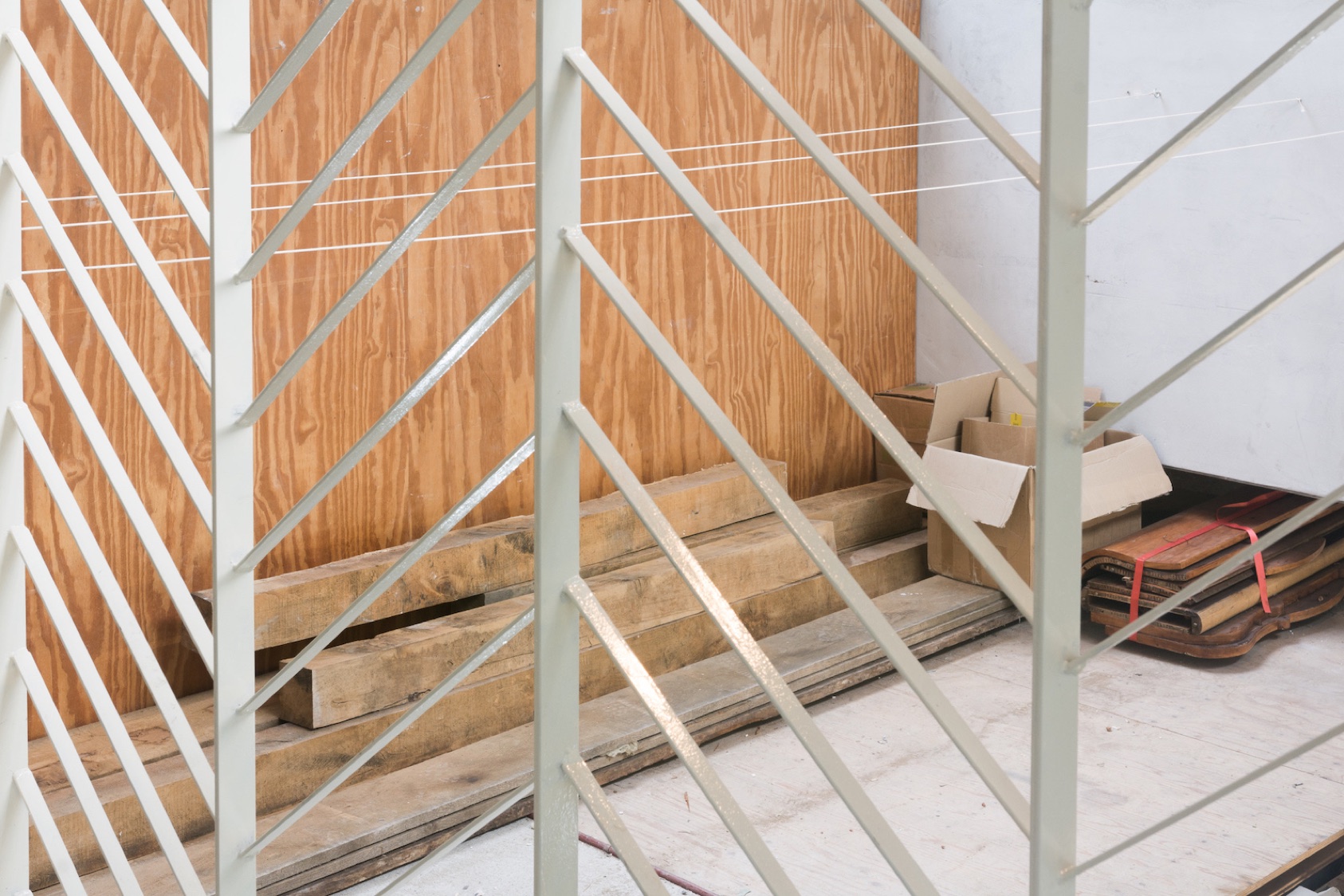 Pale yellow window grille looking onto timber and stored materials